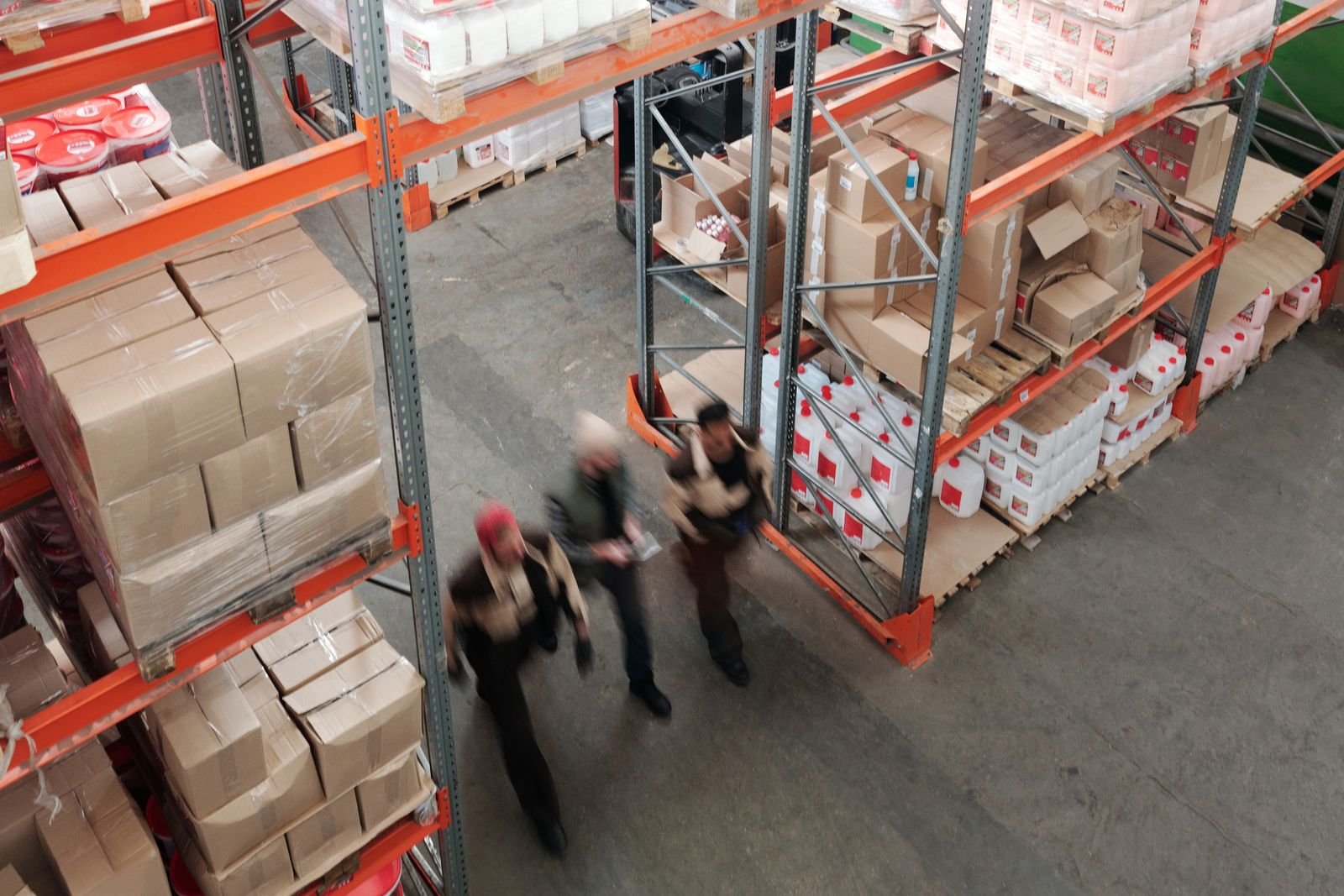 Workers moving between full shelves in a warehouse