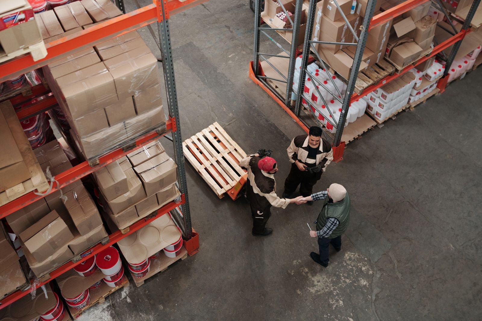 Warehouse team greeting a client between shelves of merchandise